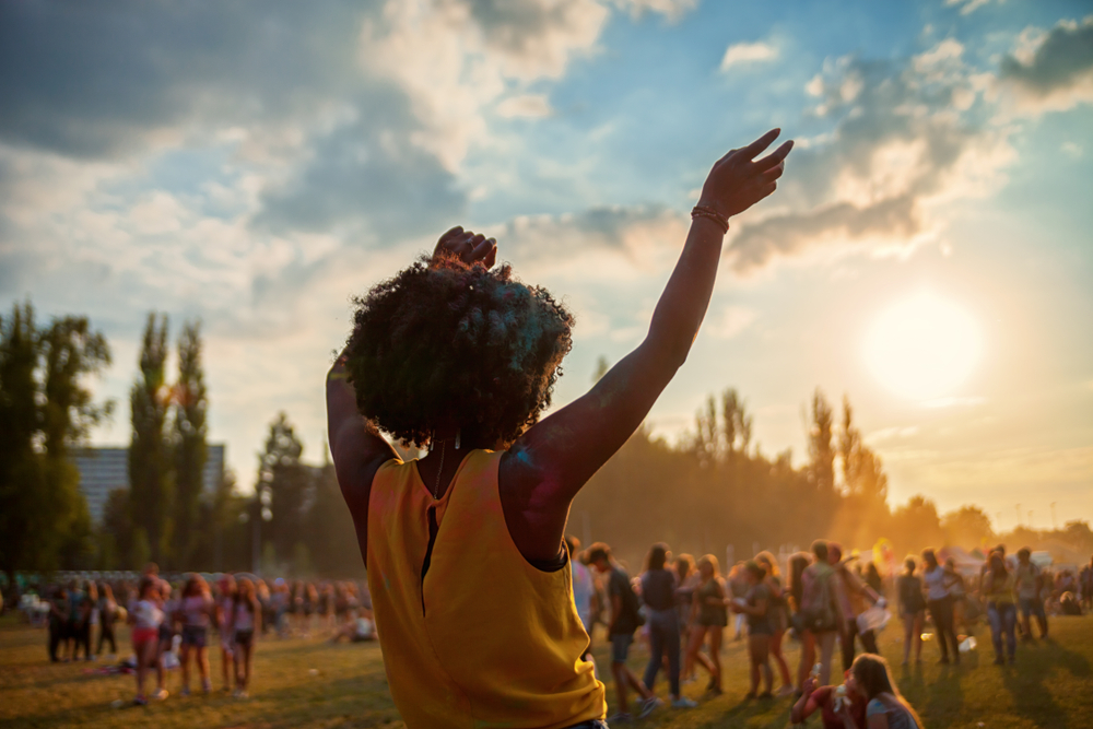 Young African american woman dancing at a summer festival with many people in the background